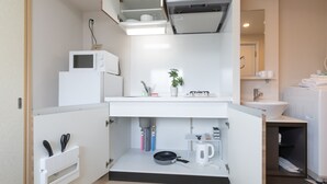 Una cocina compacta con microondas, hervidor y utensilios.