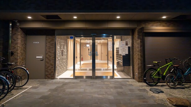 Una entrada de edificio con puerta de vidrio, estacionamiento para bicicletas y puerta de garaje.