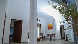 Amplio espacio interior con paredes blancas, un banco de madera, una mesa y una lámpara colgante.