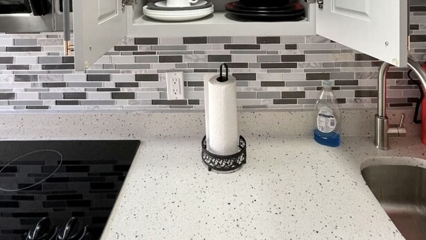 A kitchen with white cabinets, a tiled backsplash, a stainless steel sink, and a countertop with a paper towel holder and a bottle of dish soap. - COMFORTABLE ORLANDO PRIVATE STUDIO W/FULL KITCHEN! (Orlando)