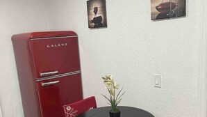 A compact kitchen with a red Galanz refrigerator, a small dining table with two chairs, and two framed pictures on the wall. - COMFORTABLE ORLANDO PRIVATE STUDIO W/FULL KITCHEN! (Orlando)