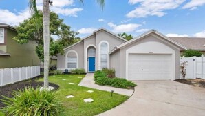 A single-story house with a garage, a front yard with a palm tree, and a clear sky.
