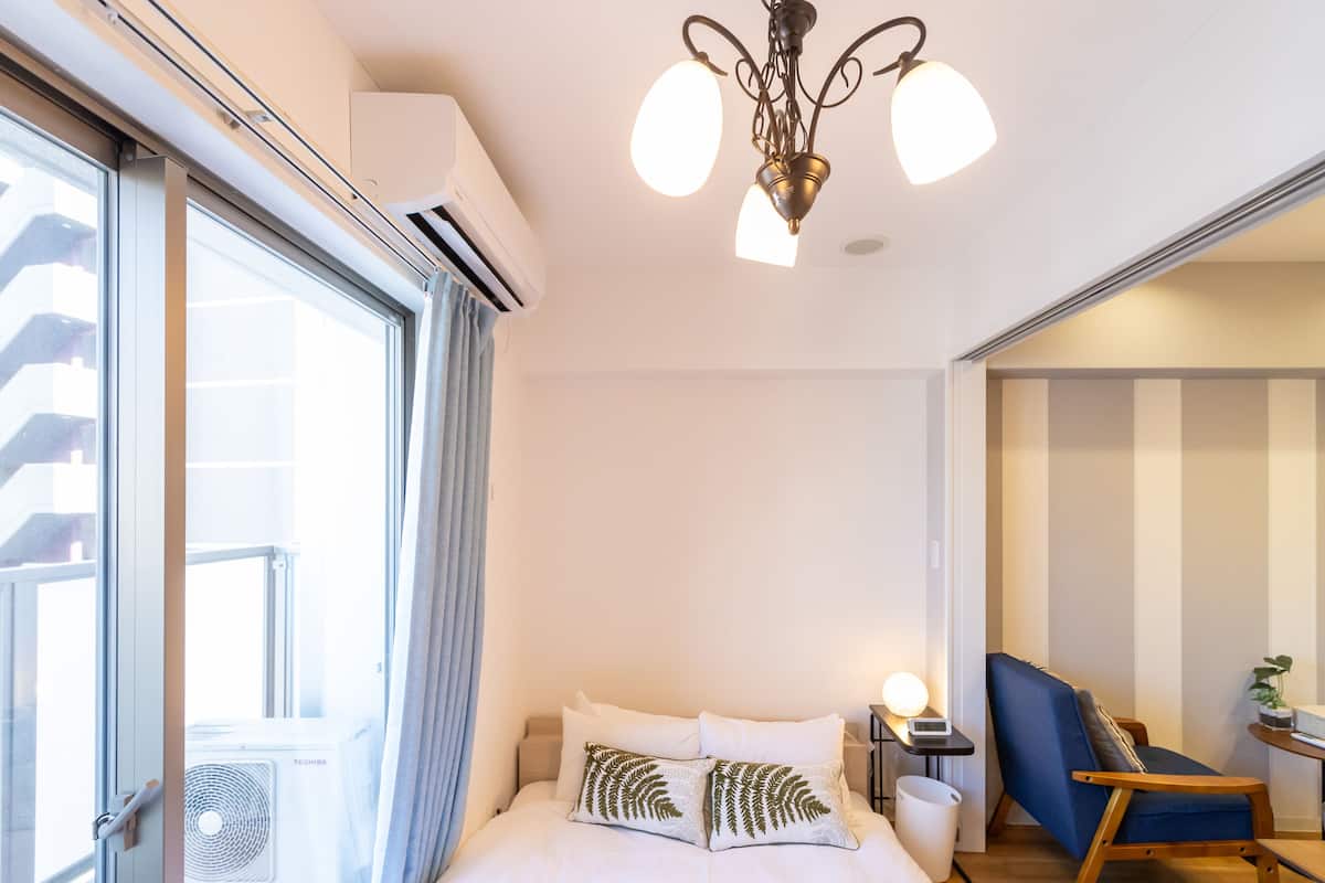 A hotel room with a bed, a desk, a chair, and a window with curtains.