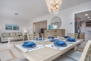 A dining area with a long table set for six, a sofa, and a chandelier. - Relax in Peace | Dog Friendly | 1 mile to Beach (Nokomis)