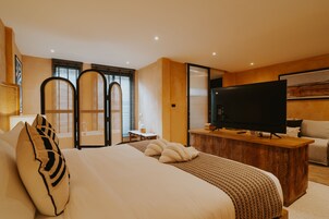 Habitación de hotel con una cama grande, un escritorio de madera con una televisión de pantalla plana, un sofá y un adorno decorativo en la pared.