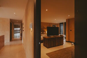 Una habitación de hotel moderna con un mostrador de recepción de madera, un televisor de pantalla plana, una cama y un baño a la vista.