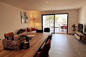 Un salon moderne avec une table à manger en bois, un canapé et un téléviseur.