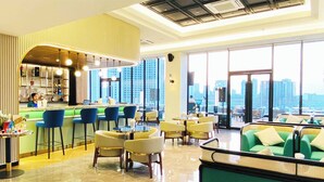 A modern hotel lobby with a bar area, seating arrangements, and large windows offering city views.