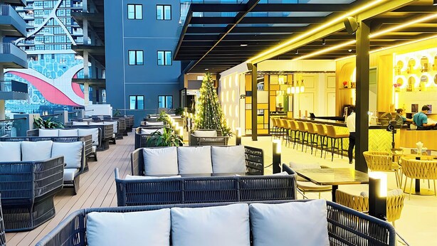 A rooftop bar with wicker furniture and a Christmas tree.