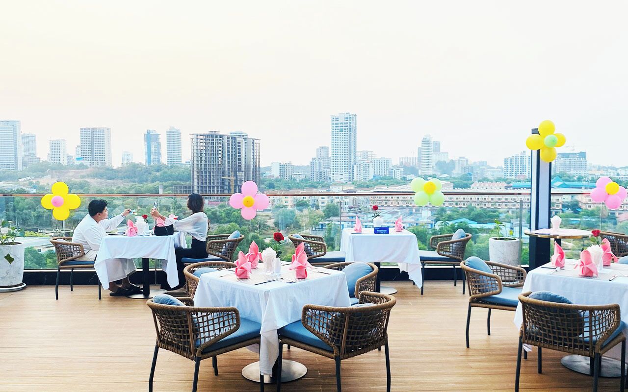 A rooftop restaurant with tables set for dining, surrounded by city views.