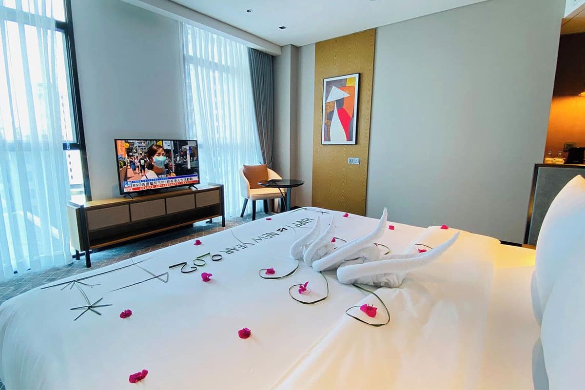 Habitación de hotel con cama, televisión, escritorio, silla y un cuadro en la pared.
