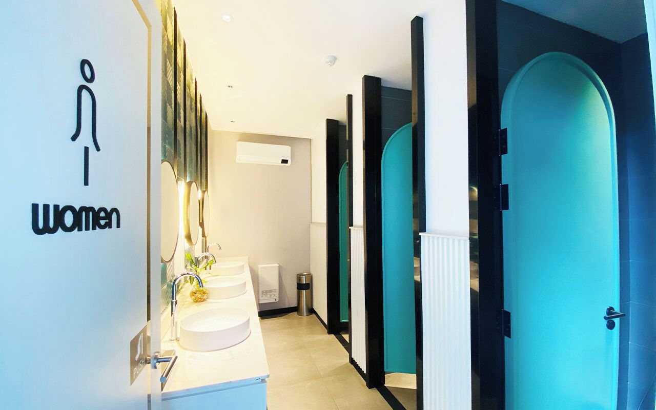 A women's restroom with a modern design, including a sink and mirror, and a sign indicating the restroom's purpose.