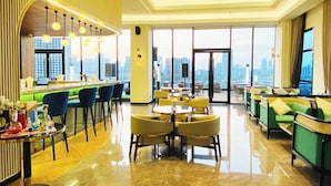 A modern hotel lobby with a bar area, seating arrangements, and large windows offering city views.
