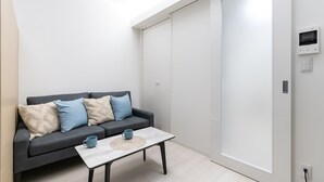A modern living room with a grey sofa, a coffee table, and a large sliding door closet.