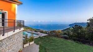 Ett modernt hus med en swimmingpool, en balkong och utsikt över havet.