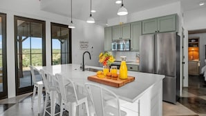 A modern kitchen with a large island, stainless steel appliances, and a view to the outdoors. - Hello Walls, Hot tub, Hill Country Views (Fredericksburg)