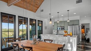 A modern kitchen with a central island, white cabinetry, and a view of the outdoors. - Hello Walls, Hot tub, Hill Country Views (Fredericksburg)
