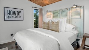 A bedroom with a large bed, wooden ceiling, and a sign that reads "HOWDY BUCKAROO'S". - Hello Walls, Hot tub, Hill Country Views (Fredericksburg)