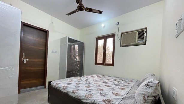 Une chambre à coucher avec un lit, un ventilateur de plafond, une armoire et une fenêtre avec des stores.
