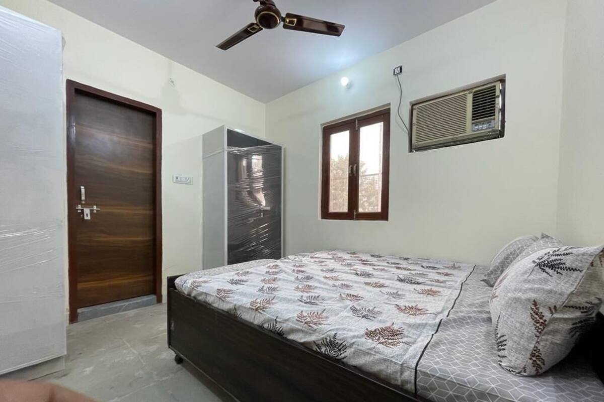 Un dormitorio con cama, ventilador de techo, ventana y puerta.
