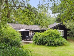 A traditional wooden house with a tiled roof, surrounded by lush greenery and a small patio with outdoor furniture. - "Neela" - 300m from the sea by Interhome (Væggerløse)
