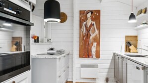 A modern kitchen with white cabinetry, a wooden floor, a large painting on the wall, and pendant lighting. - "Neela" - 300m from the sea by Interhome (Væggerløse)