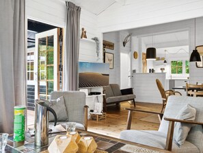 A modern living room with a large window, a fireplace, and a dining area with wooden furniture.