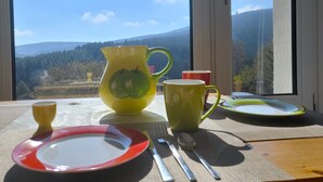 A table set with plates, a pitcher, and cups, with a scenic mountain view through a window. - Oberwiesenthal, Unweit der Skipiste (Oberwiesenthal)