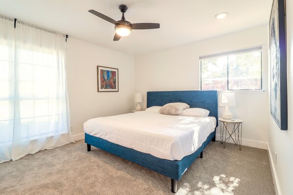 A bedroom with a bed, a ceiling fan, a window, and a nightstand.
