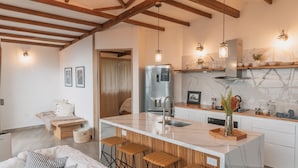 A modern kitchen with a marble countertop, wooden bar stools, and a built-in island. - TERRAMIA ESTATE (Santa Marta)