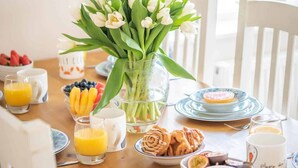 A breakfast table with a vase of white tulips, fruit bowls, and orange juice glasses. - High Tide -  a house that sleeps 6 guests  in 3 bedrooms (Salcombe)
