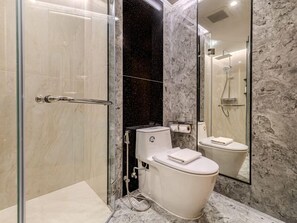 Un baño moderno con ducha de vidrio, inodoro y pared de mármol.