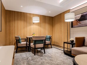 Un interior moderno con un panel de madera en la pared, suelo de mármol y una zona de comedor con sillas y una mesa.