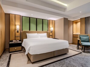 Ein modernes Hotelzimmer mit einem großen Bett, einem Nachttisch, einem Sessel und einem Schreibtisch.