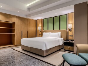 Ein modernes Hotelzimmer mit einem großen Bett, einem Holzschrank, einer grünen Akzentwand und einem Nachttisch mit Lampe.