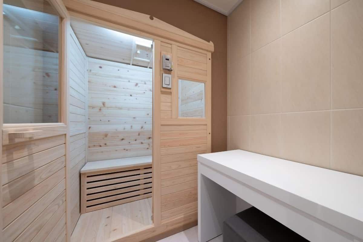 Un sauna avec des murs en bois et un banc blanc.