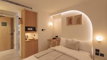 Une chambre d’hôtel moderne équipée d’un lit, d’une table de chevet et d’une petite kitchenette.