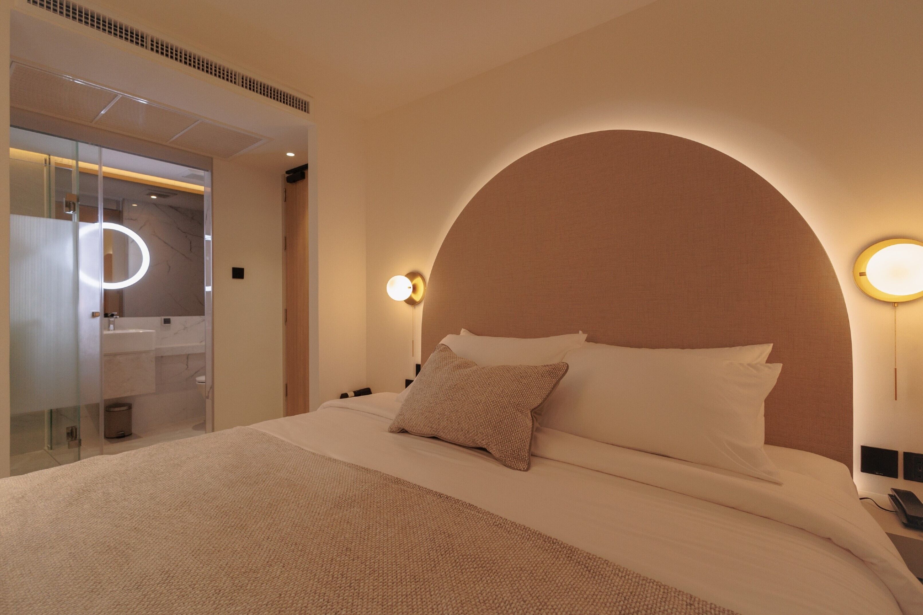 Ein Hotelzimmer mit einem großen Bett, einem in Glas eingefassten Badezimmer und einem modernen Design.