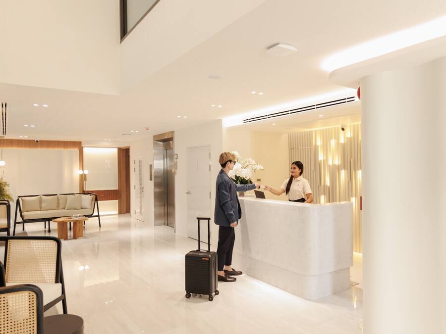A modern hotel lobby with a reception desk, a sofa, and a coffee table.