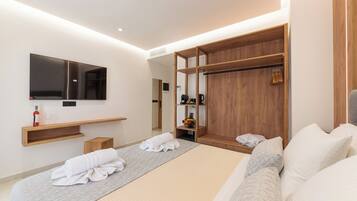 Una habitación de hotel moderna con una cama grande, un armario de madera, un televisor de pantalla plana y una mesita de noche de madera.