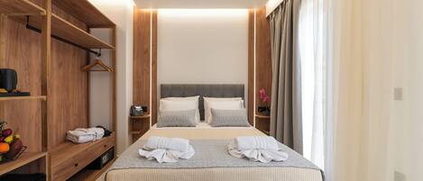 Un dormitorio moderno con una cama grande, un armario de madera y una mesita de noche con lámpara.