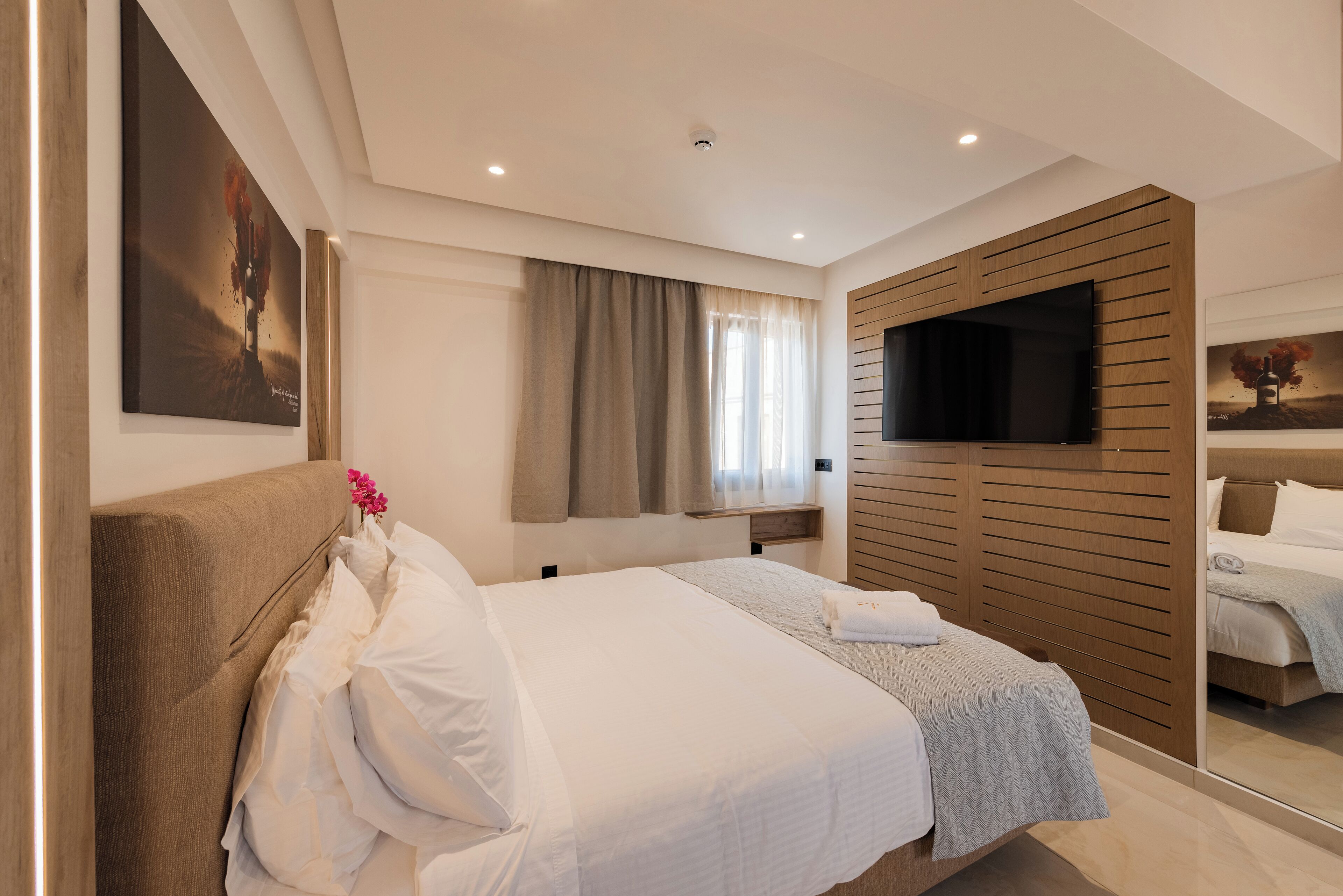 Une chambre d’hôtel moderne avec un grand lit, une télévision et un miroir.