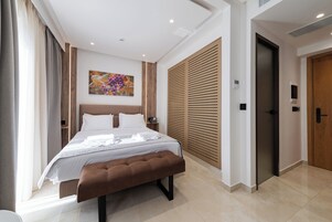 Un dormitorio moderno con una cama grande, cabecera de madera, un banco y una obra de arte colgada en la pared.