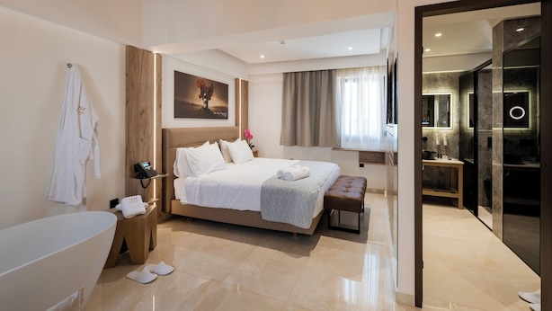 A modern hotel room with a large bed, a separate bathroom, and a walk-in closet. - The Wine Hotel (Rhodes)