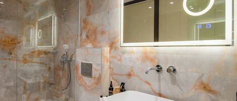 Une salle de bain moderne avec une baignoire sur pieds, une douche à parois de verre et un pare-baignoire en marbre.