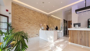 A modern reception area with a marble counter, wooden wall paneling, and potted plants. - The Wine Hotel (Rhodes)