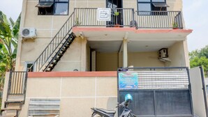 Un edificio de dos pisos con un balcón, una escalera y una motocicleta estacionada en frente.