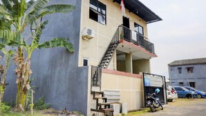 Un edificio de dos pisos con un balcón, una bandera y vehículos estacionados.