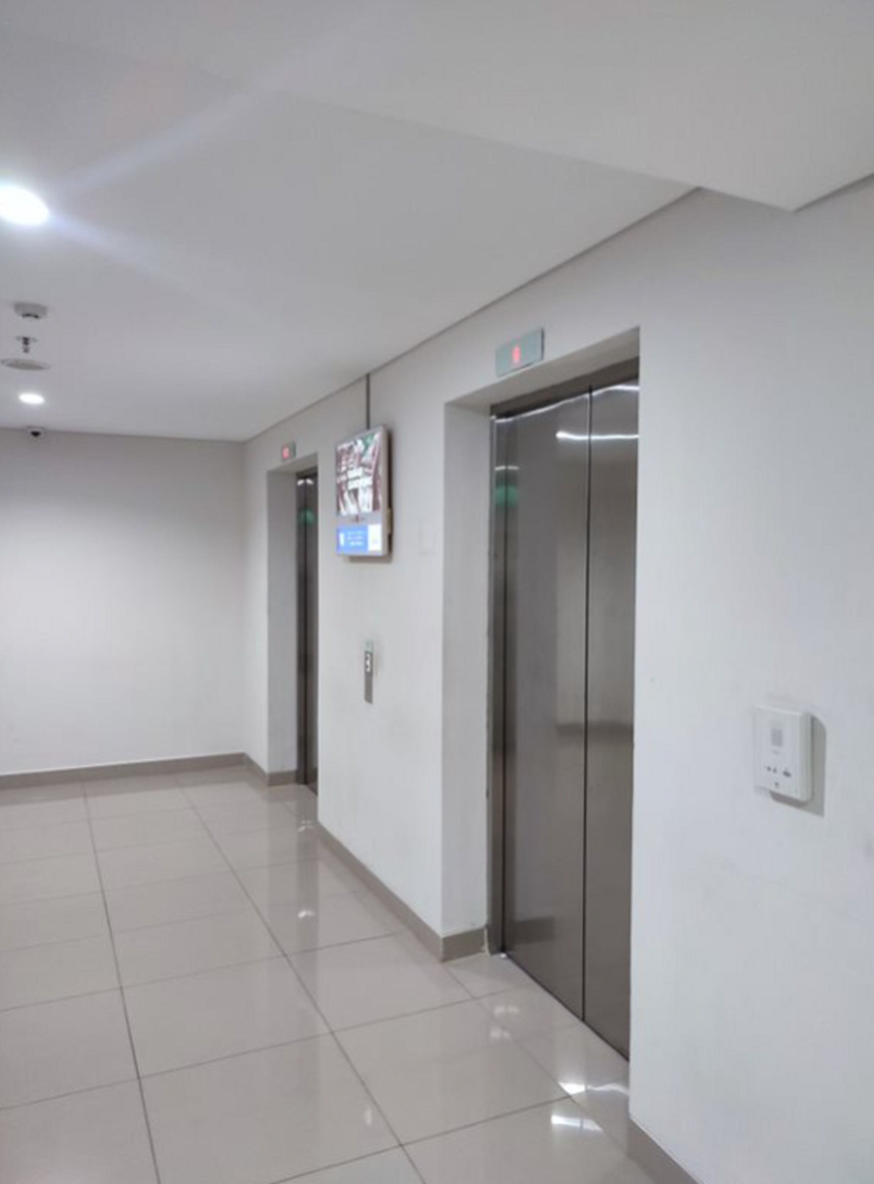 Un pasillo con dos ascensores y un cartel en la pared.
