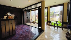 A reception area with a tiled floor, a reception desk, and a seating area with chairs and a table. - Na Thapae Chiangmai Hotel (Chiang Mai)